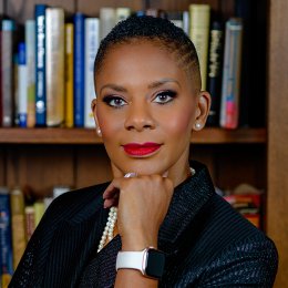 Dr Daria J Wilis standing in front of a bookshelf