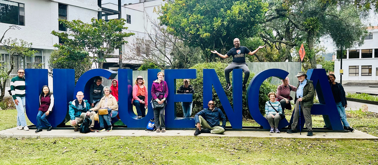 A group photo of smiling travelers in front of a UCUENCA sign in Ecuador.